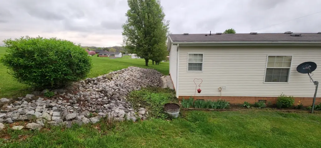 Rock-lined drainage swale beside a white house
