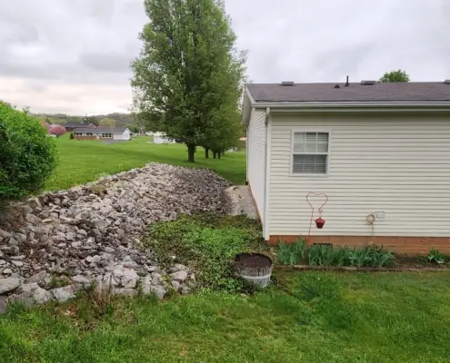 Rock-lined drainage swale beside a white house