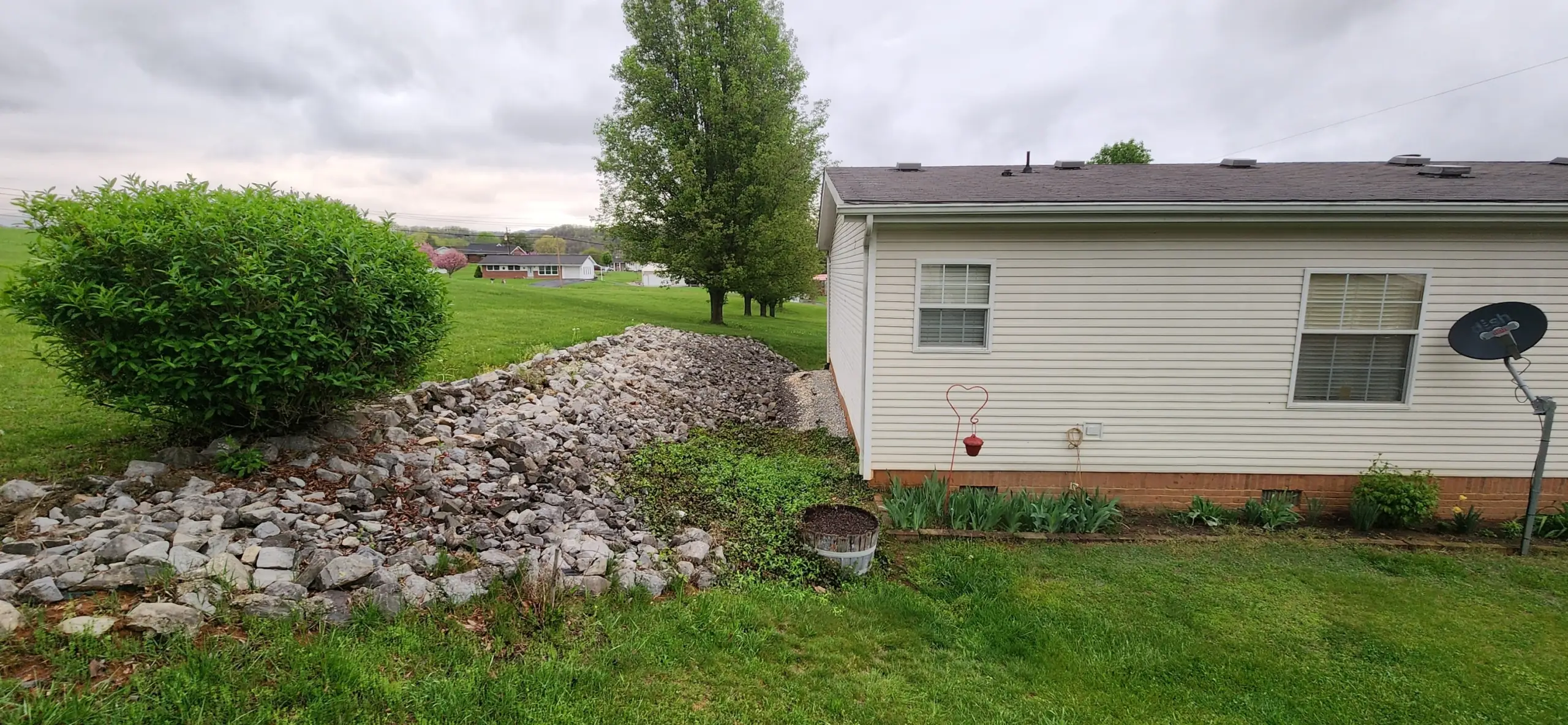 Rock-lined drainage swale beside a white house