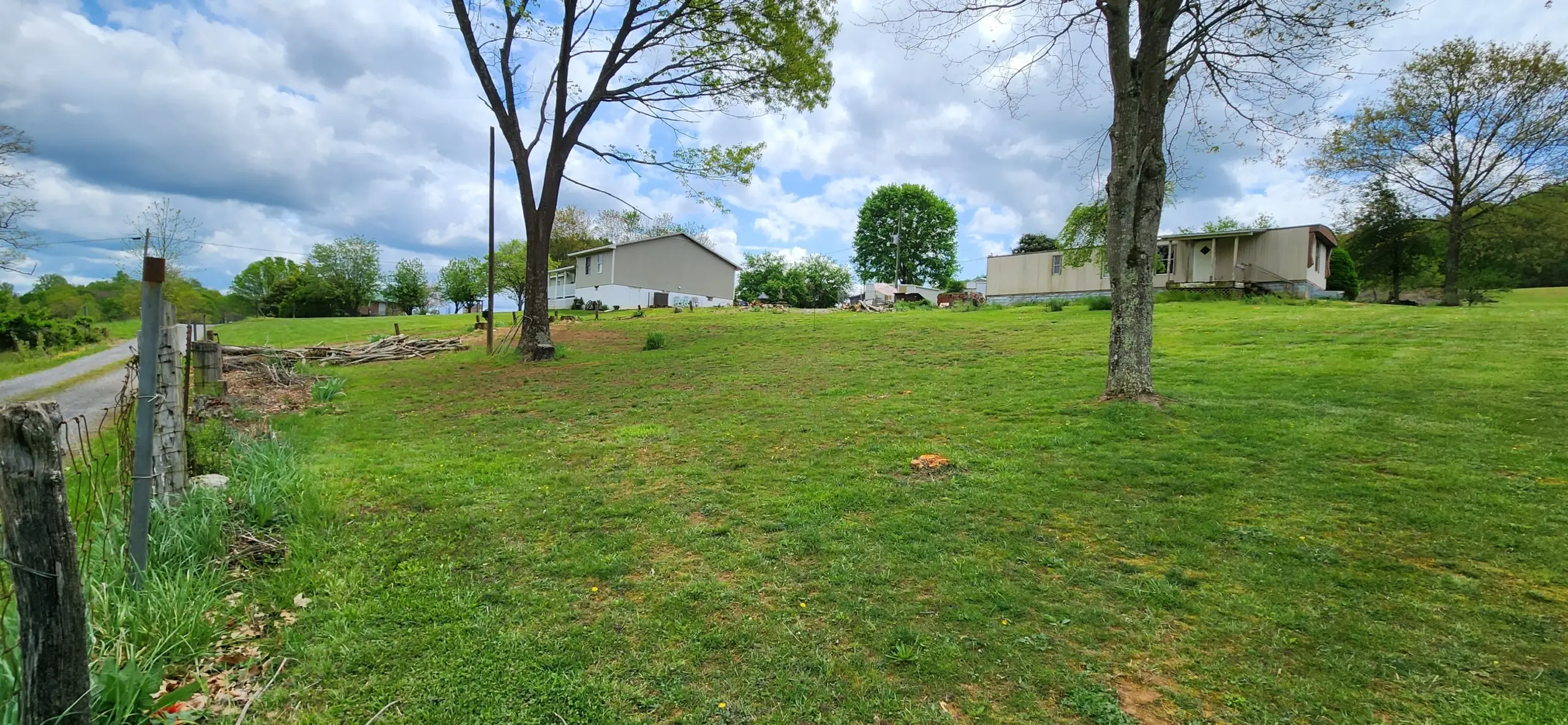 Mowed hillside yard with homes and shade trees