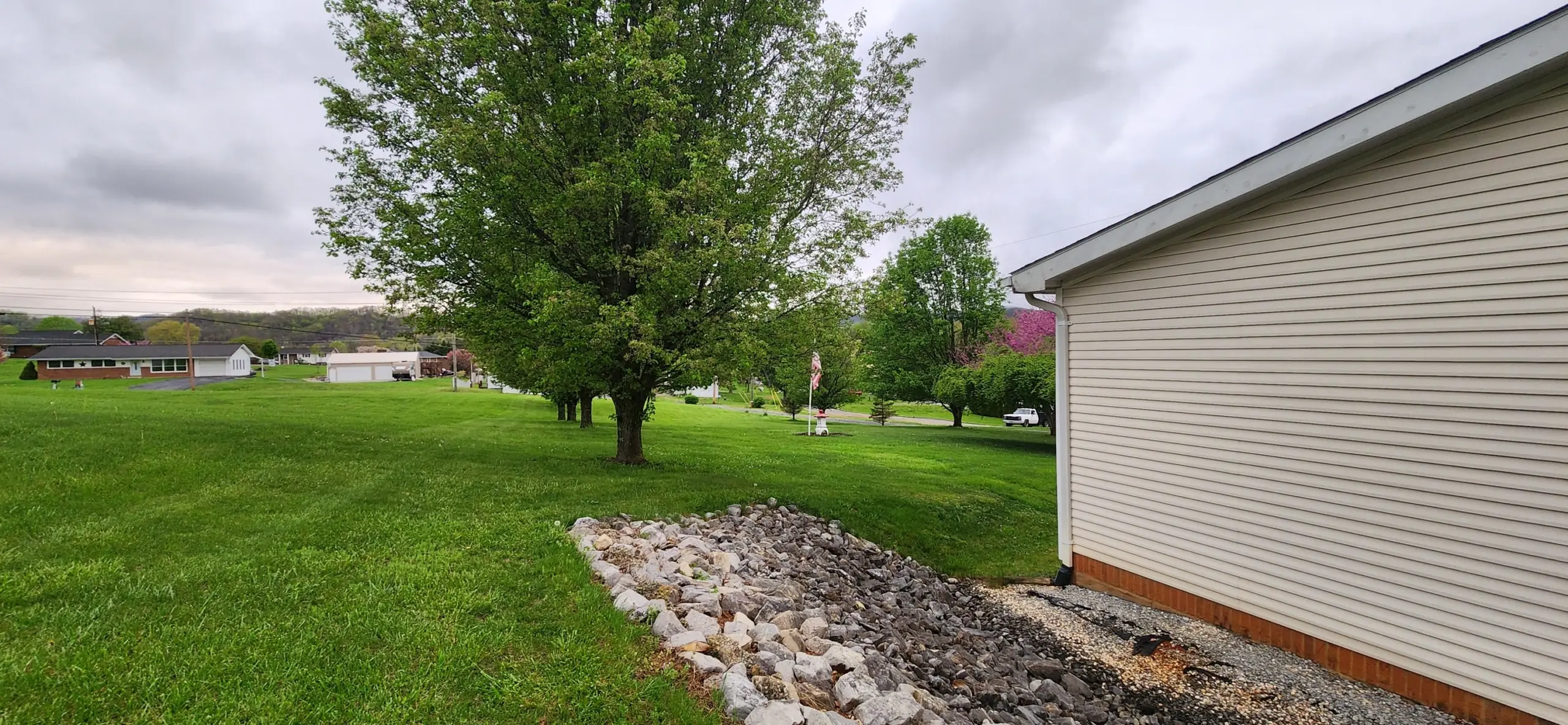 Rock drainage bed and mowed lawn beside a white house