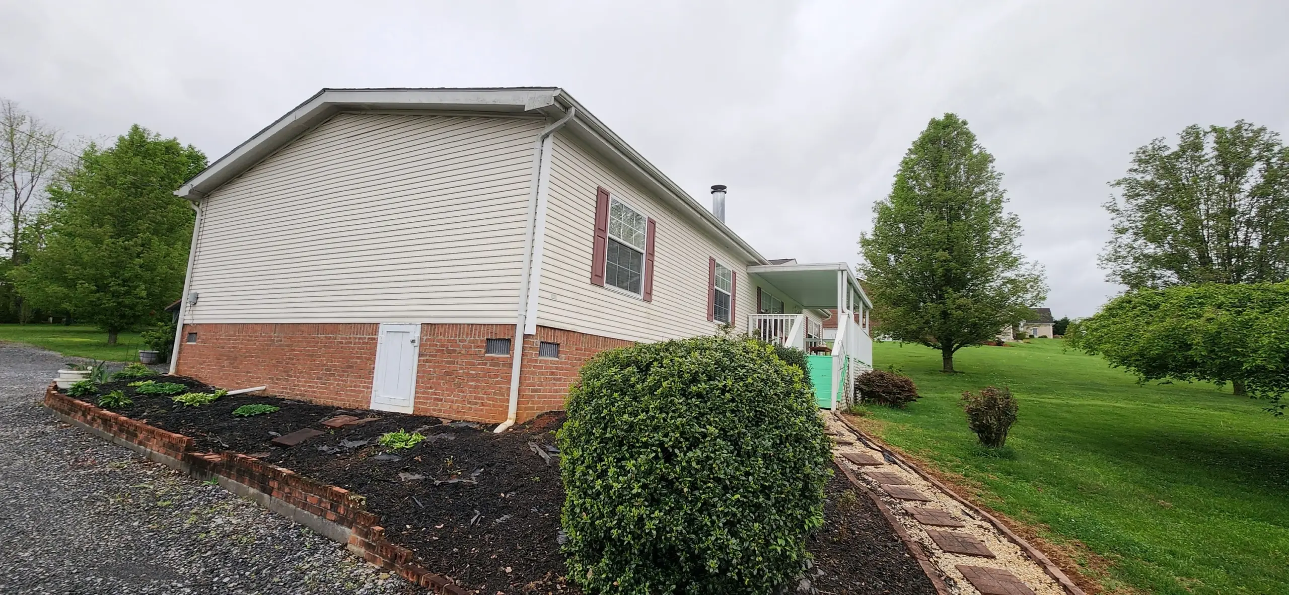 Mulched flower bed and paver walkway along a white home