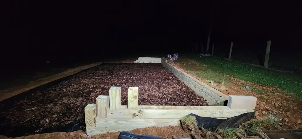 Timber-framed play area filled with wood mulch at night
