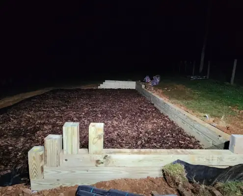 Timber-framed play area filled with wood mulch at night