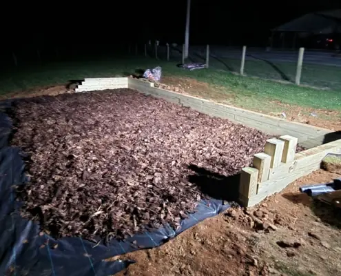 Timber-bordered mulch bed with steps at night