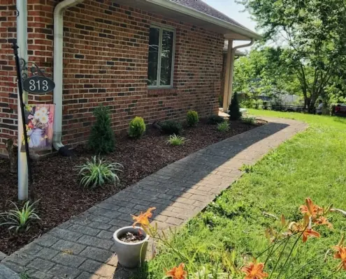 Fresh mulch beds and a paver walkway at a brick home
