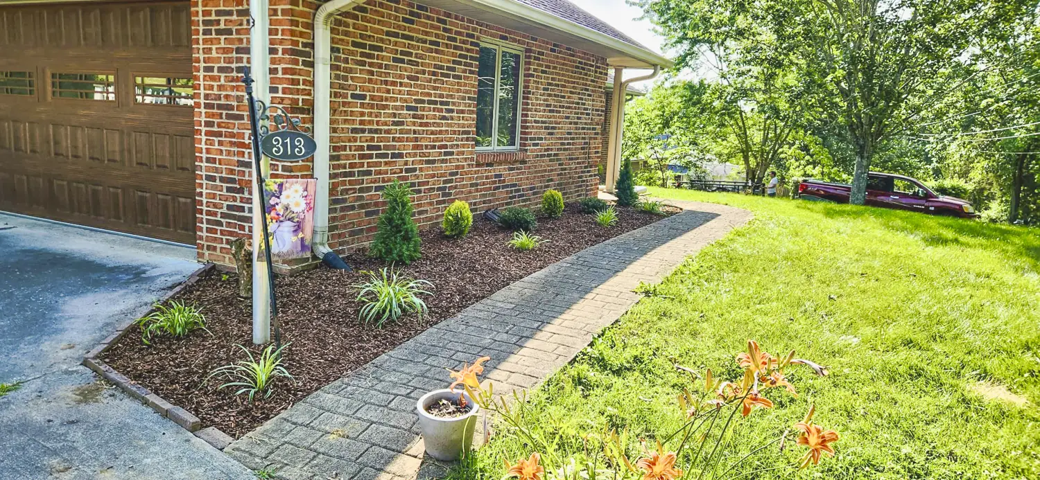 Fresh mulch beds and a paver walkway at a brick home